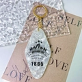 Macro detail of white marble acrylic diamond keychain with outdoor life mountain engraving - Gold Accessories / White