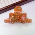 Close-up of orange amber pattern acetate bow hair claw clip with France Handmade gold text - Orange