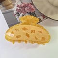 Detailed close-up of yellow marble textured acetate hair claw with unique geometric cutouts - Mango