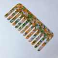 Dettaglio di un pettine per capelli quadrato in acetato con trama mimetica arancione e verde - verde-giallo
