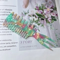 Detail view of acetate fishbone comb with mint green marble texture and wide teeth - Pink Green Marble