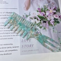 Close-up of a wide-tooth acetate hair comb with marble patterns on a magazine - Cyan Marble