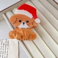 Detalle de una pinza para el pelo de caniche marrón con un gorro navideño rojo festivo - Perro con Gorro de Navidad