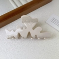 Detail einer cremefarbenen LOVE-Haarklammer mit Herzrelief auf einer strukturierten Oberfläche - Weiß