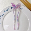 Dettaglio di una forcina a U con design a farfalla, perle e trama effetto marmorizzato - Viola