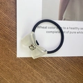 Detailansicht eines cremefarbenen Harz-Haargummis mit Schleife und quadratischem Strass - Schwarzes Gummiband - Transparentes Weiß