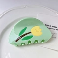 Close-up of a light green tulip hair claw clip made of glossy acetate on a white plate - Green