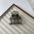 Detail of a dark gray translucent resin hair claw clip with golden metal spring on a tray - Transparent Black