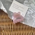 Macro detail of a pale pink translucent resin hair claw clip on a textured background - Pink