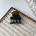 Deep green resin hair claw clip with glossy finish on a decorative jewelry tray - Green