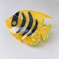Macro detail of fish-shaped acetate hair claw featuring yellow patterns and green fins - Yellow