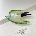 Detail van de vogelvormige acetaat haarklem op linnen dienblad met een kunstpapierkaart - Groen
