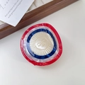 Rood wit blauw gestreepte acetaat haarklem met een geel zonnegezicht embleem erop - Rode Zon