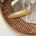 Close-up of champagne leaf oval barrette with Barrette la France text on white tissue - Yellow