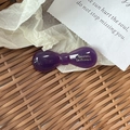 Detailed view of a purple acetate bow hair clip with gold metal lettering on fabric - Candy Bow Knot / Purple