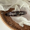 Dettaglio del fermaglio per capelli ovale in acetato con texture marmorizzata marrone - Marrone