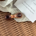 Detail einer bernsteinfarbenen Acetat-Haarspange mit goldener Logo-Beschriftung - Karamell