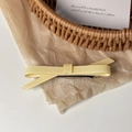 Gros plan d'une pince à cheveux nœud jaune crème sur un fond esthétique épuré - Jaune Clair