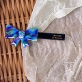 Detailed close-up of marble pattern acetate bow hair clip with gold lettering - Blue