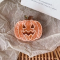 Detail shot of orange pumpkin claw clip with a spooky face on textured acrylic material - 4.7cm x 4cm / Orange Pumpkin Shape