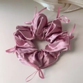 Dettaglio di un elastico per capelli in raso rosa con nastri e piccoli fiocchi - Rosa