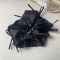 Detail of a black silk scrunchie with delicate ribbon bows on a gray background - Black