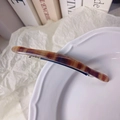 Detailed view of amber marble resin hair clip on white decorative ceramic plate - Coffee