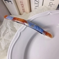Détail de la pince à cheveux en acétate marbré avec texture d'encre bleue et orange sur plat - Bleu-Marron
