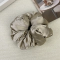 Detailed view of champagne gold satin scrunchie with glossy pleated silk texture - Champagne