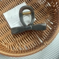 Elegant dark grey bow claw clip with golden metal spring inside a woven basket - Grey
