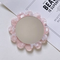 Detalle de espejo de maquillaje floral en acetato rosa sobre escritorio minimalista - Rosa