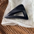 Minimalist matte black triangular hair claw clip displayed in a rustic woven basket - Matte Black