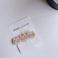 Detailed macro view of three cat-shaped acetate hair clips with gold accents on a display card - Beige