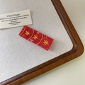 Detail of red marble-textured acrylic hair clip with golden symbolic patterns - Red Envelope