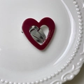 Detail of burgundy heart hair clip with gold text on a white ceramic plate - Hollow Heart / Red