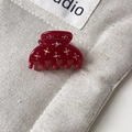Gros plan d'une mini pince à cheveux bordeaux ornée de fleurs en strass brillants - Rouge