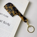 Close-up of tortoise shell acetate portable comb keychain on a book background - Gold Clasp / Leopard Print