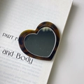 Nahaufnahme von herzförmigem Taschenspiegel mit Schildpattmuster auf antikem Buch - Spiegel-Zubehör (5.9cm*5.4cm 13g)