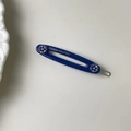 Detalle de una pinza para el pelo azul oscuro con diamantes de imitación y texto dorado - Azul