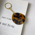 Makro-Detail von bernsteinfarbenem Schildpatt-Kamm-Schlüsselanhänger mit goldenem Ring - Kamm-Schlüsselanhänger (4.9cm*4.2cm 7g)