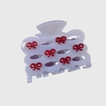 Detail view of a lavender acetate hair claw with delicate red 3D bow accents - Purple