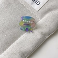 Makroaufnahme einer Mini-Regenbogen-Haarklammer mit Perlen auf beigem Canvas-Hintergrund - Ca. 2,5 cm / Irisierendes Grün