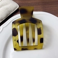 Flat square tortoiseshell hair clip in matte amber finish on a minimalist ceramic plate - Frosted Leopard