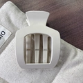 Pince à cheveux carrée mate crème sur sac en toile montrant un accessoire géométrique - Blanc