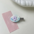 Dettaglio del fermaglio per capelli ovale blu con fiore su un piatto di ceramica bianca - Piccolo fiore viola