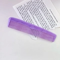 Macro detail of purple marble acetate comb with anti-static teeth on paper background - Purple