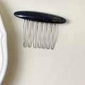 Dettaglio del pettine per capelli in acetato fatto a mano con logo dorato e otto rebbi - Nero