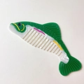 Dettaglio di un pettine in acetato a forma di pesce con finitura perlata e denti larghi - Pettine Pesce Verde Bianco