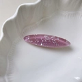 Elegante pinza ovalada morada con brillos de concha sobre un plato de cerámica - Morado