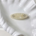 Macro detail of oval cream hair clip featuring butterfly relief and sparkling rhinestones - Mermaid Color